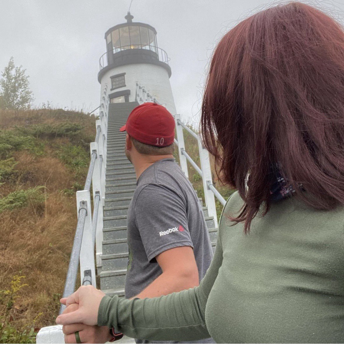 Me and my husband walking toward a lighthouse in Maine hand in hand.