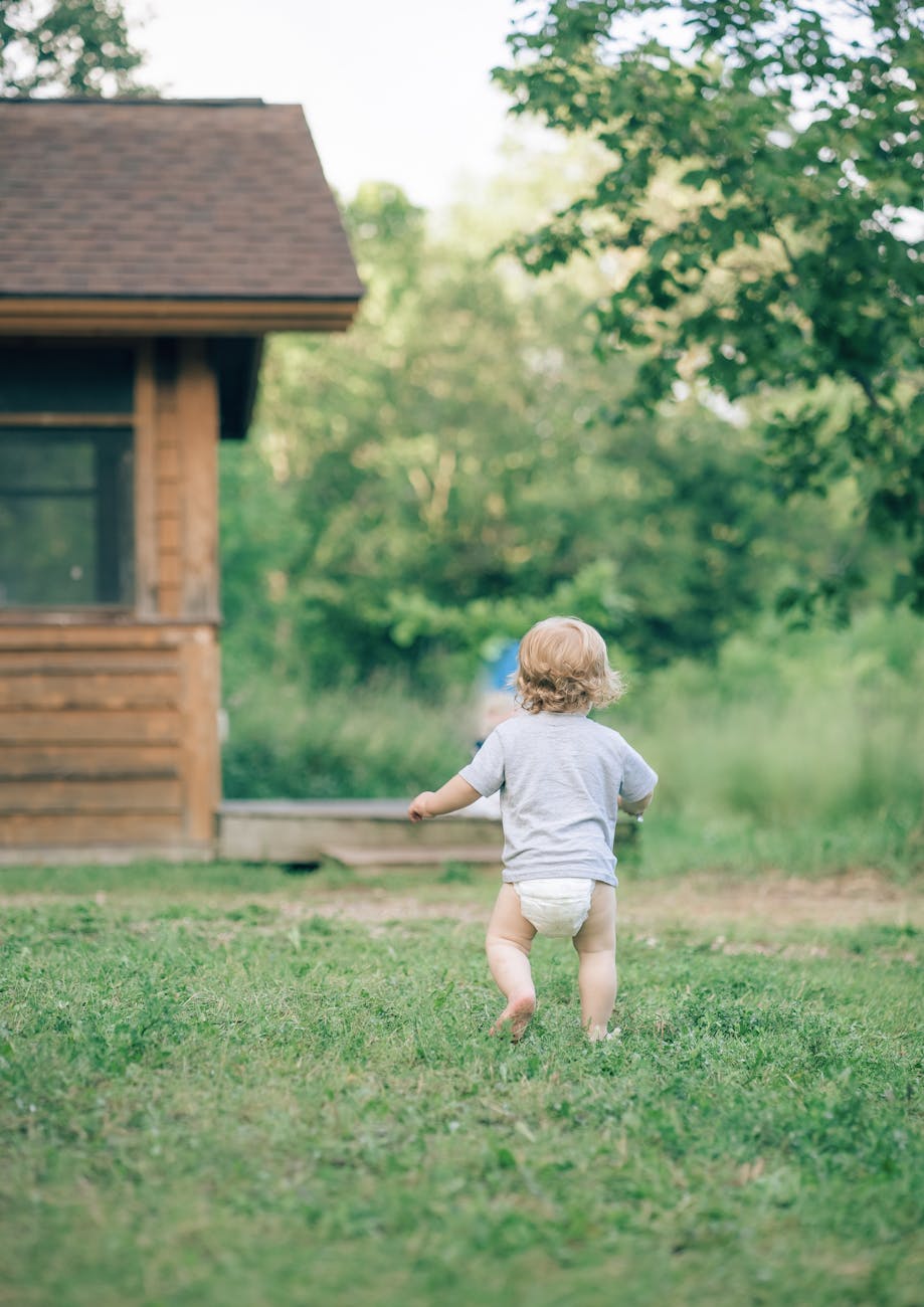 back view of a toddler in a diaper running in the garden